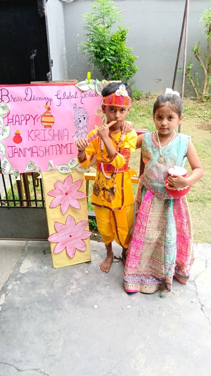 Two students posing beside their handmade Janmashtami display